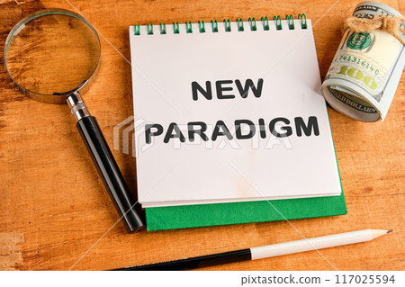 New paradigm motivational phrase in a notebook in a composition with a magnifying glass, dollars and a pencil 117025594