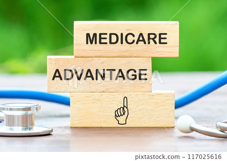 Medicare Advantage text on wooden blocks against a background of blurred green plants 117025616