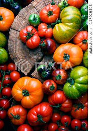 Different sizes and varieties ripe tomatoes on wooden cutting board 117026398