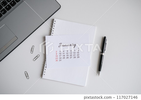 January calendar, notepad and laptop on the office table 117027146