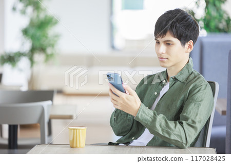 A man operating a smartphone in a cafe 117028425