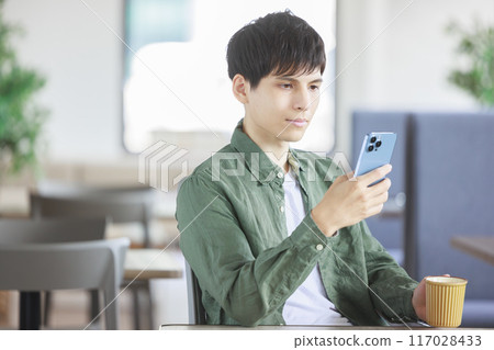 A man operating a smartphone in a cafe A man operating a smartphone in a cafe 117028433