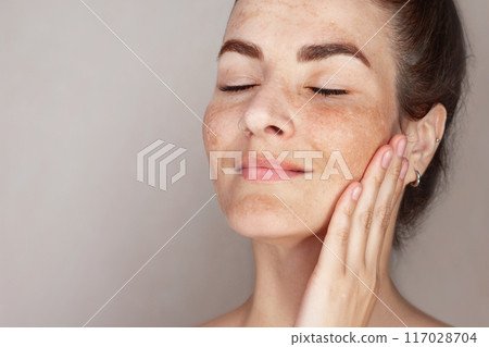 Caucasian woman's face with freckles or age spots, she loves her skin Caucasian woman's face with freckles or age spots, she loves her skin 117028704