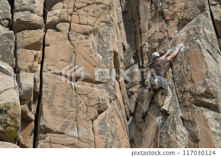 Rock climbing on towering granite cliffs, professional rock climber climbs cliff, extreme sport 117030124