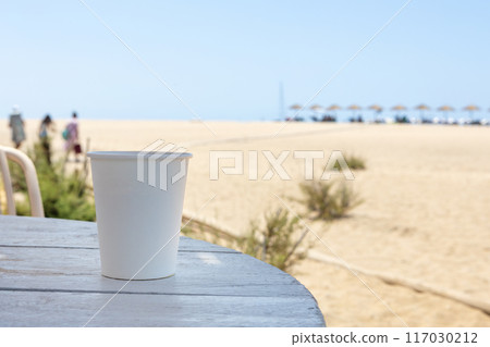 Disposable Cup on Beach Table with Sandy Shore View Disposable Cup on Beach Table with Sandy Shore View 117030212