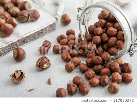 Raw healthy organic hazelnut nuts snack in glass jar on white kitchen table. 117030278