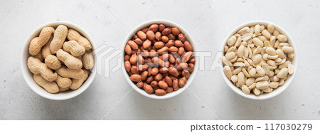 Whole and peeled with blanched and salted peanut nuts in bowls on light background. 117030279