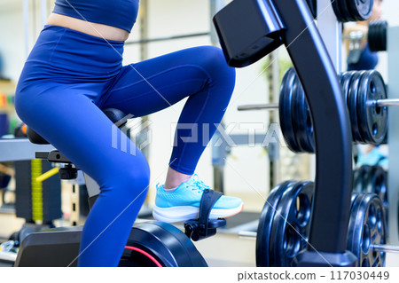 Woman working out at the gym, exercise bike, fitness bike, muscle training girl, diet, lower body, no face 117030449