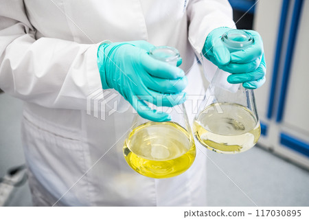 Bottom view of a chemist shaking yellow samples before analysis Bottom view of a chemist shaking yellow samples before analysis 117030895