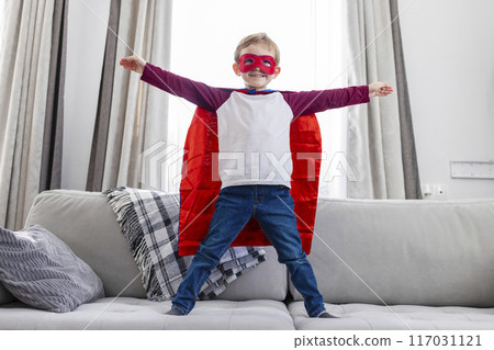 Boy dressed as superhero on couch Boy dressed as superhero on couch 117031121