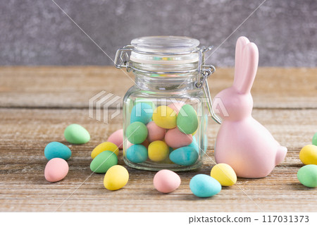 Easter composition with pink bunny and a jar with colorful candies. 117031373