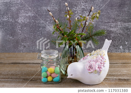 Easter colorful candies, pussywillow and a figurine of bird on the table. Easter colorful candies, pussywillow and a figurine of bird on the table. 117031380