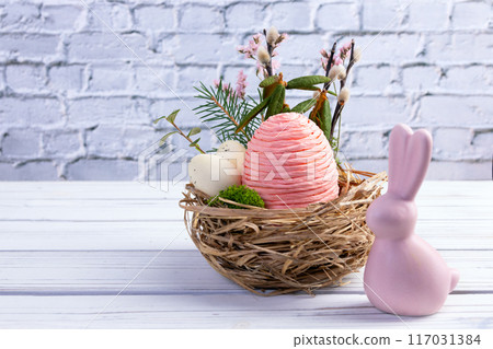 Easter nest with eggs and branches, bunny on the white table. 117031384