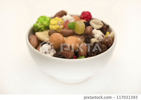 Sweet assorted nuts and dried fruits in a plate on a white background. Sweet assorted nuts and dried fruits in a plate on a white background. 117031393