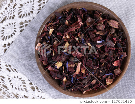 Tea mix of karkade, flowers and berries in a saucer and on the textile. Tea mix of karkade, flowers and berries in a saucer and on the textile. 117031450