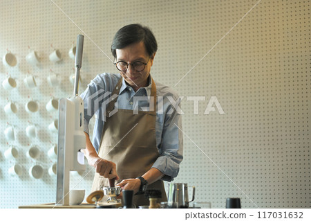Stylish mature barista wearing apron preparing coffee for customers at minimal cafe 117031632