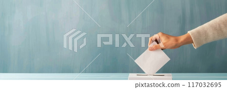 Hand Inserting Ballot Into Light Blue Box Against Teal Background Hand Inserting Ballot Into Light Blue Box Against Teal Background 117032695