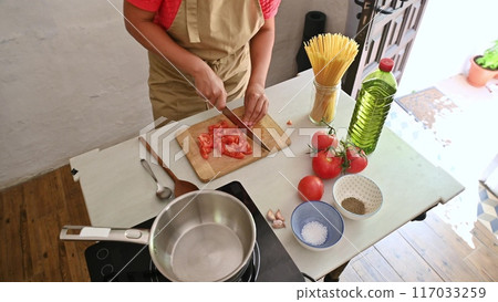 Housewife woman chef in kitchen apron cooking, preparing Italian meal in the home kitchen Housewife woman chef in kitchen apron cooking, preparing Italian meal in the home kitchen 117033259