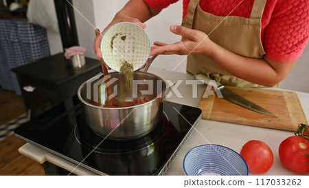 Housewife woman chef in kitchen apron cooking, preparing Italian meal in the home kitchen Housewife woman chef in kitchen apron cooking, preparing Italian meal in the home kitchen 117033262