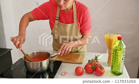 Housewife woman chef in kitchen apron cooking, preparing Italian meal in the home kitchen 117033268