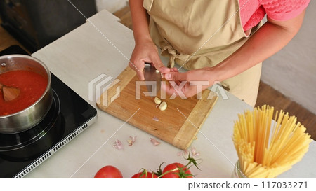 Housewife woman chef in kitchen apron cooking, preparing Italian meal in the home kitchen Housewife woman chef in kitchen apron cooking, preparing Italian meal in the home kitchen 117033271