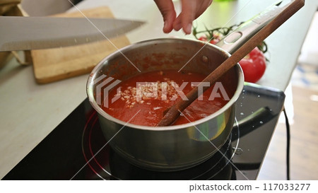 Housewife woman chef in kitchen apron cooking, preparing Italian meal in the home kitchen Housewife woman chef in kitchen apron cooking, preparing Italian meal in the home kitchen 117033277