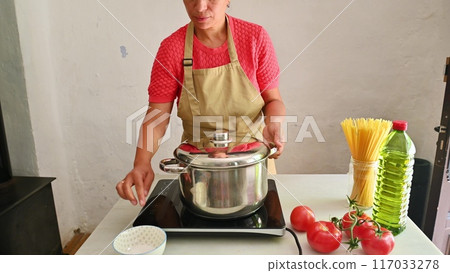 Housewife woman chef in kitchen apron cooking, preparing Italian meal in the home kitchen 117033278
