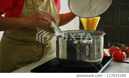 Housewife woman chef in kitchen apron cooking, preparing Italian meal in the home kitchen Housewife woman chef in kitchen apron cooking, preparing Italian meal in the home kitchen 117033280