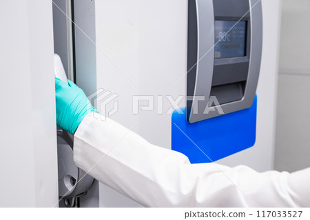 Woman hand opening a -80 C freezer with samples. Woman hand opening a -80 C freezer with samples. 117033527