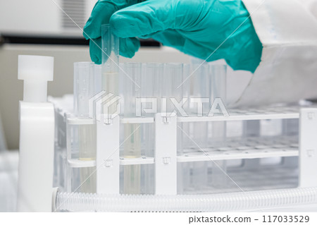 Close up of a woman inserting tubes into a fraction collector connected to an HPLC system Close up of a woman inserting tubes into a fraction collector connected to an HPLC system 117033529
