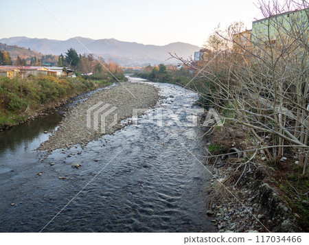 A shallow fast river. Stream with shallows. Fast river in the city. Concrete rapids on the river. River in Georgia. A shallow fast river. Stream with shallows. Fast river in the city. Concrete rapids on the river. River in Georgia. 117034466
