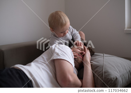 Cute little toddler girl walking over father, sleeping in bed in the morning. Cute little toddler girl walking over father, sleeping in bed in the morning. 117034662