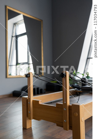 Pilates equipment. Reformer bed. Reformer pilates studio machine for fitness workouts in gym. Fit, healthy and strong authentical body. Fitness concept Pilates equipment. Reformer bed. Reformer pilates studio machine for fitness workouts in gym. Fit, healthy and strong authentical body. Fitness concept 117034793