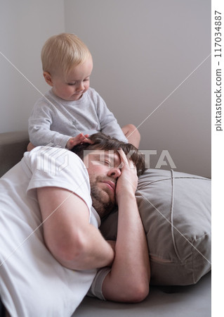 Cute little toddler girl walking over father, sleeping in bed in the morning. Cute little toddler girl walking over father, sleeping in bed in the morning. 117034887