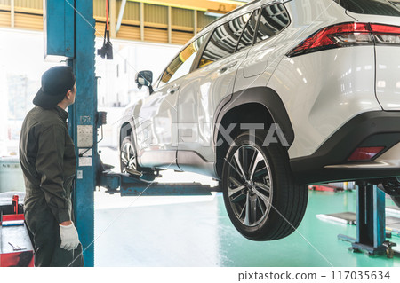 一名男性機械師在維修店舉起車輛 117035634