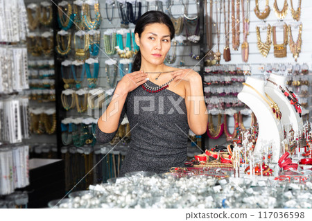 Adult woman chooses and buys beads from various precious stones in jewelry store 117036598