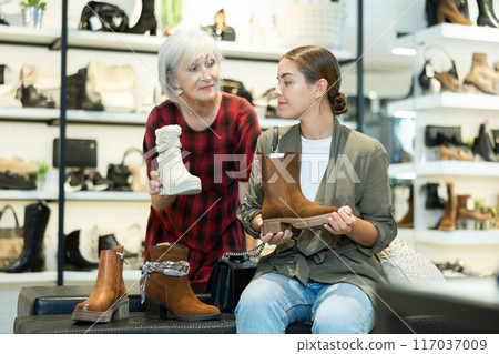 Young girl with elderly mother choosing demi-season footwear in shoe boutique Young girl with elderly mother choosing demi-season footwear in shoe boutique 117037009