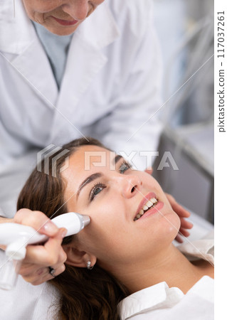 Young woman having face vacuum cleaning procedure Young woman having face vacuum cleaning procedure 117037261