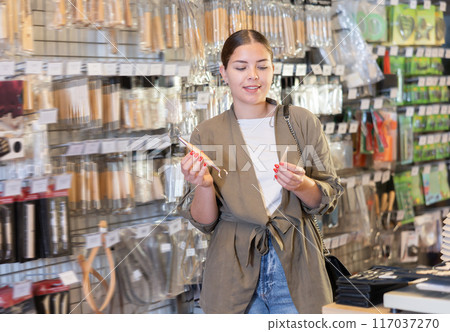 Female customer chooses set of tools, stacks for modeling, working with clay, plasticine and ceramics in specialized store 117037270