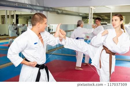 Young woman in kimono practicing kicking paired with male partner Young woman in kimono practicing kicking paired with male partner 117037309