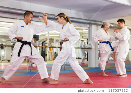 Young woman in kimono sparring with male partner during martial arts training 117037312