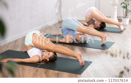 Mom, grandma and teenage daughter do Halasana plow pose. Mom, grandma and teenage daughter do Halasana plow pose. 117037614