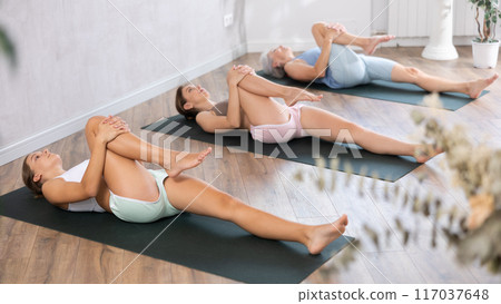 Teenage girl doing yoga in group in studio 117037648