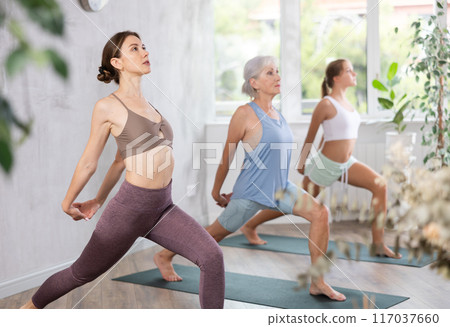 Mom, grandma and teenage daughter do variation of pose warrior virabhadrasana pose 117037660