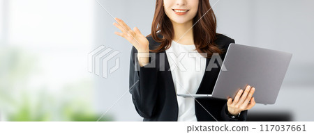 A smiling Japanese businesswoman holding a laptop and giving directions 117037661