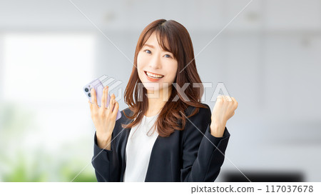 Smiling Japanese business woman holding a smartphone Smiling Japanese business woman holding a smartphone 117037678