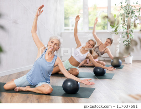 Family of three generations doing soft ball pilates exercises during group pilates class in studio 117037681