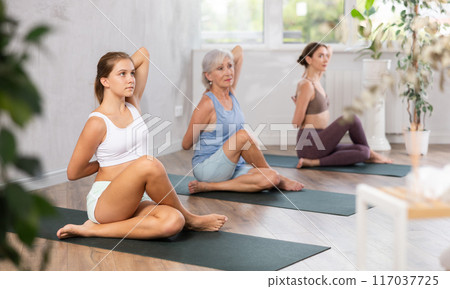 Teenage girl doing yoga in group in studio 117037725