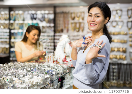 Happy asian woman showing rings in jewelry showroom Happy asian woman showing rings in jewelry showroom 117037726