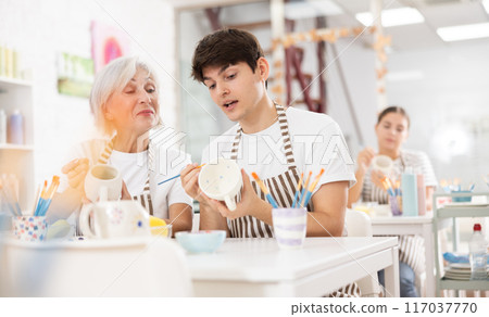 Cheerful guy working with elderly mother in family pottery studio 117037770